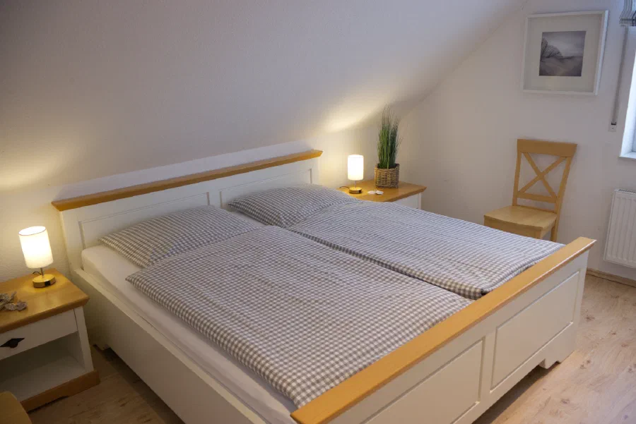 Doppelbett in einem hellen Schlafzimmer im Dachgeschoss.
